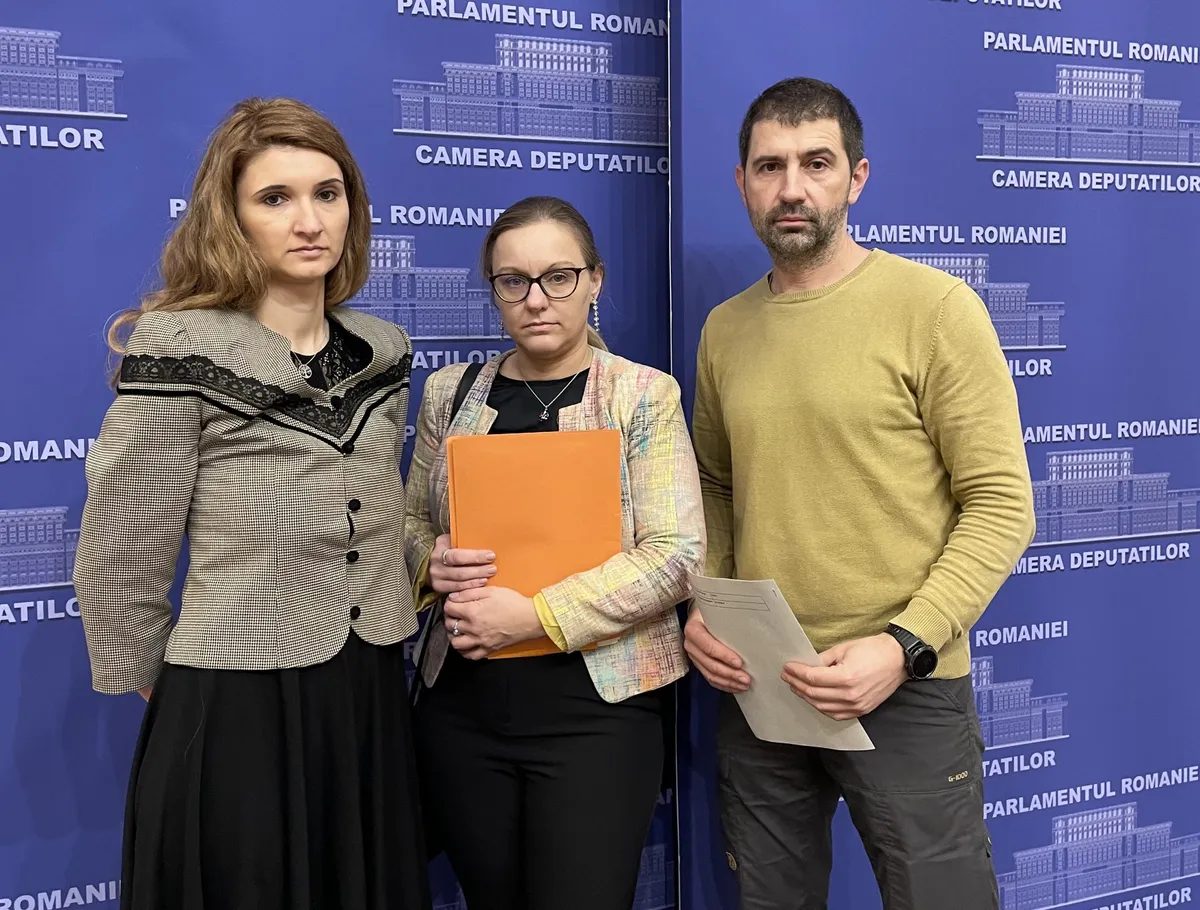 Trei persoane în fața unui panou al Parlamentului României, ținând documente.