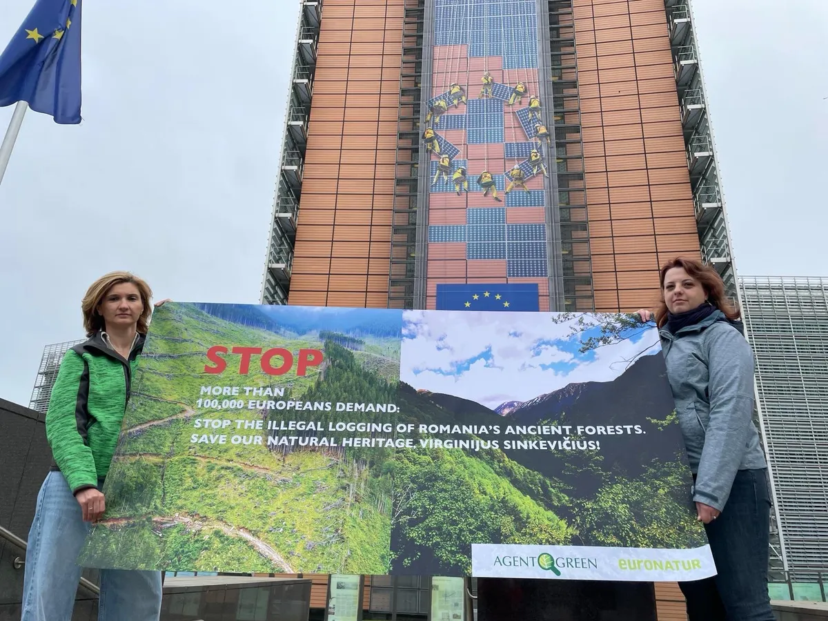 Două participante țin un banner pentru pădurile României în fața clădirii Berlaymont